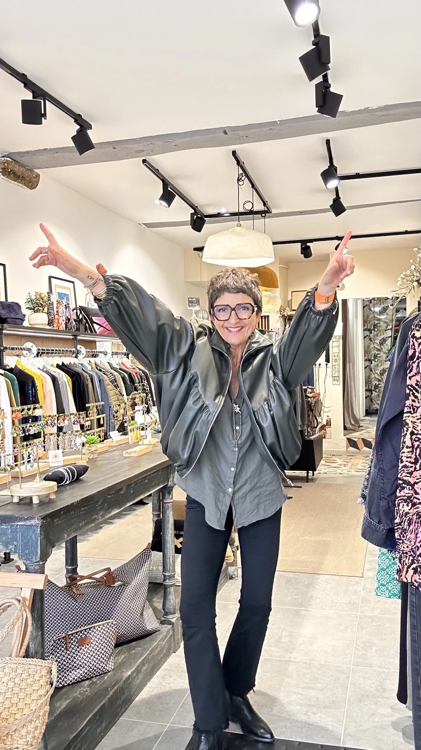 Céline souriante, les bras levés, dans sa boutique